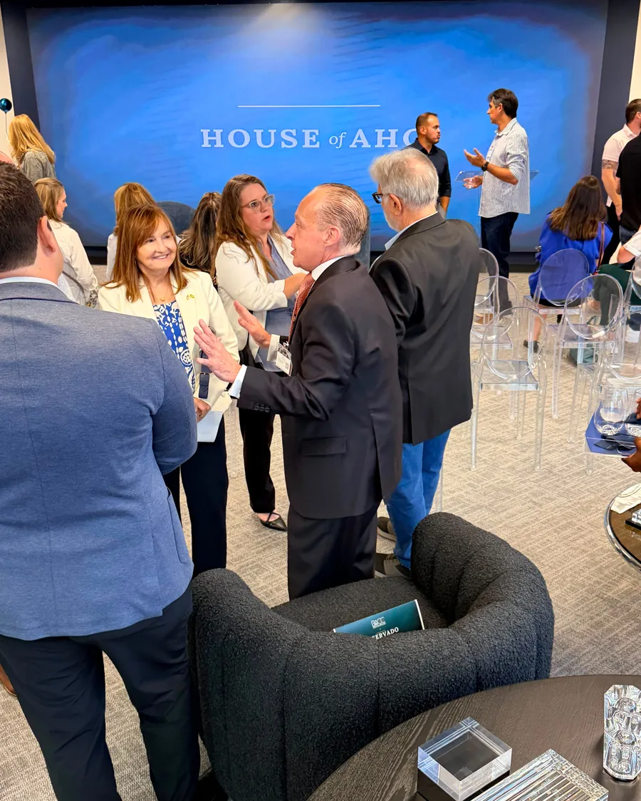 Guests talking in small groups after the talk, with the House of AHC logo on the screen